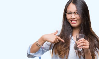 Genç Asyalı kadın sürpriz yüz işaret parmağı kendini izole arka plan üzerine bir bardak su içme