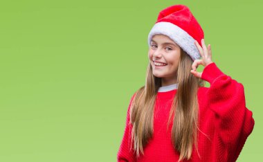 Genç güzel kız izole arka plan el ve parmaklar ok işaretiyle yapıyor olumlu gülümseyen üzerinde Noel şapka giyiyor. Başarılı ifade.