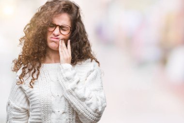 Güzel esmer kıvırcık saçlı Genç kız acı ifadesi ile el ile ağız diş ağrısı veya dişlerde dişlerle ilgili hastalık nedeniyle dokunmadan izole arka plan üzerinde kış kazak giyiyor. Diş hekimi kavramı.