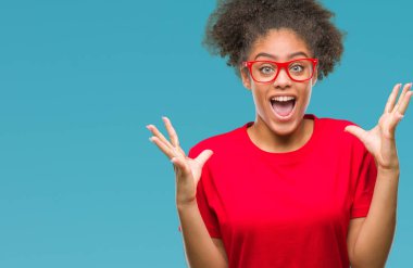 Üzerinde gözlük takan genç afro Amerikalı kadın deli kutluyor arka plan izole ve silah ile başarı için yükseltilmiş ve açık gözleri heyecanlı çığlık hayrete düşürdü. Kazanan kavramı