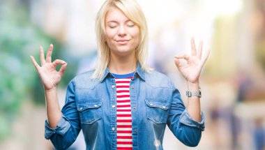 Genç güzel sarışın kadın giyiyor denim ceket izole arka plan üzerinde dinlenmek ve gülümseyen gözlerle kapalı parmak jestle meditasyon yapıyor. Yoga kavramı.