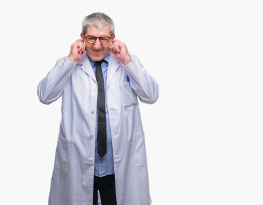 Yakışıklı kıdemli Doktor, yüksek sesle müzik gürültü rahatsız ifade parmaklarıyla kulaklarıyla kapsayan arka plan üzerinde beyaz önlük giyen bilim adamı profesyonel adam izole. Sağır kavramı.