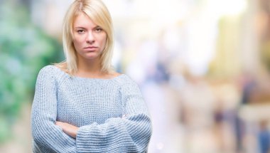 İzole arka plan şüpheci ve sinir, onaylamayan ifade yüz çapraz kolları üzerinde kış kazak giyen genç güzel sarışın kadın. Negatif kişi.