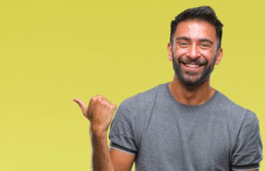 Seyir ve başparmak yanında yukarıyı mutlu yüz ile gülümseyen izole arka plan yetişkin İspanyol adam.