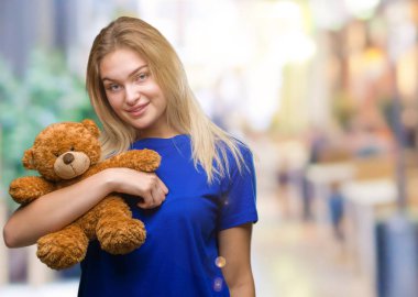 Sevimli Ayıcık izole arka plan üzerinde duran ve diş gösterilen kendine güvenen bir gülümsemeyle gülümseyerek mutlu bir yüz tutan genç beyaz kadın