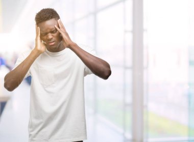Çünkü baş baş ağrısı için üzerinde el ile beyaz t-shirt giyen genç Afro-Amerikan adam stres. Migren muzdarip.