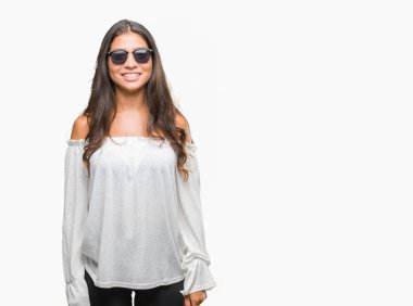 Genç güzel Arap kadın yüzünde mutlu ve güzel bir gülümseme ile izole arka plan üzerinde güneş gözlüğü takıyor. Şanslı kişi.