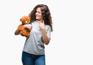 Oyuncak ayı izole arka plan üzerinde çok mutlu el ve parmak ile işaret tutan genç esmer kız