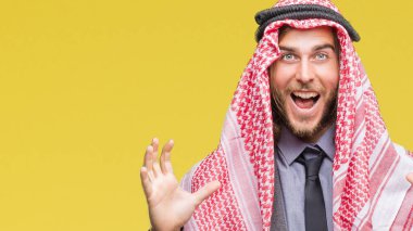 Uzun saçlı keffiyeh üzerinde giyen genç yakışıklı Arap adam deli kutluyor arka plan izole ve başarı için kaldırdı kollarını açarak hayrete ve heyecanlı çığlık gözleri açık. Kazanan kavramı