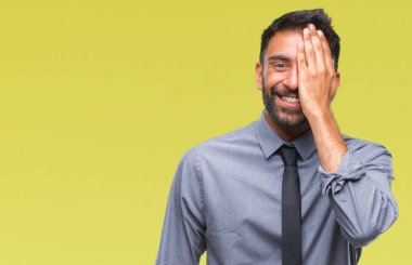 Yetişkin İspanyol iş adamı el yüz ve sürpriz duygu kendinden emin gülümseme ile tek gözüyle kapsayan izole arka plan üzerinde.