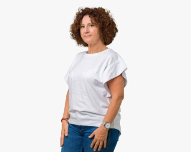Üzerinde beyaz t-shirt giyen güzel orta ager üst düzey kadın arka plan gevşek yüzünde ciddi bir ifade ile izole. Basit ve çapraz silah ile doğal