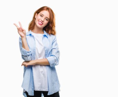 Genç güzel iş kadını mutlu yüz zafer işareti yaparken kameraya göz kırpıyor ile gülümseyen izole arka plan üzerinde. İki numaralı.