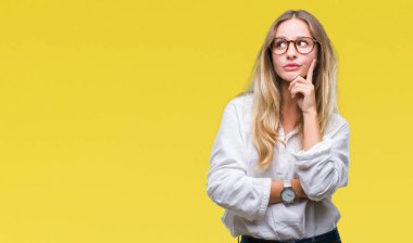 Genç güzel sarışın iş kadın gözlük ile izole arka plan üzerinde çene düşünme hakkında soru, dalgın ifade ver. Düşünceli yüzüyle gülümsüyor. Şüphe kavramı.