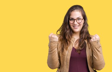 Artı boyutu giyen genç kadın güzel bir elbise ve deri şaşırmış ve başarı için hayran kaldırdı kollarını açarak kutlama izole arka plan üzerinde ceket ve gözleri açık. Kazanan kavramı.