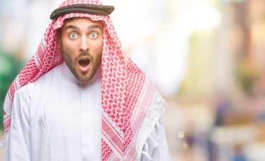 Keffiyeh izole arka plan korkuyor ve şok sürpriz ifade, korku ve heyecan yüz üzerinde giyen genç yakışıklı adam.
