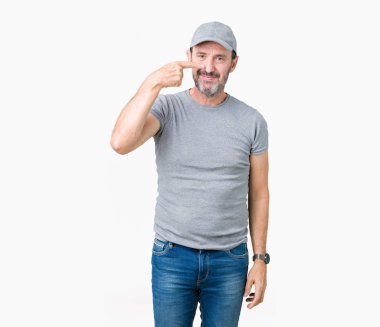 Yakışıklı orta yaş ağarmış kıdemli adam giyiyor spor kap üzerinde izole yüz ve burun, neşeli gülümseyerek el parmak ile işaret arka plan