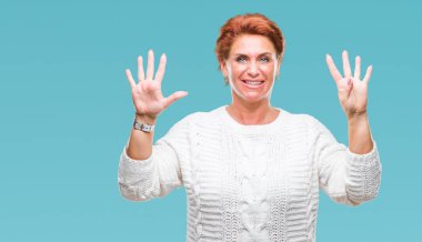 Gösterilen arka plan üzerinde kış kazak giyen Atrractive üst düzey beyaz Kızıl saçlı kadın izole ve parmakları ile işaret numara 9 kendinden emin ve mutlu gülümseyerek süre.