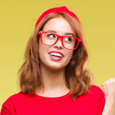 Seyir ve başparmak yanında yukarıyı mutlu yüz ile gülümseyen izole arka plan üzerinde genç güzel kadın.