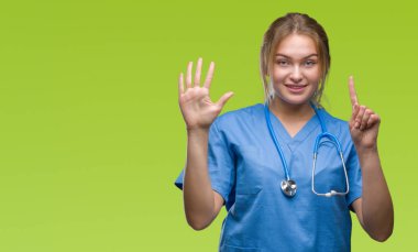 Gösterilen arka plan üzerinde cerrah üniforma giyen genç beyaz doktor kadın izole ve parmakları ile işaret kendinden emin ve mutlu gülümseyerek süre 6 numara.