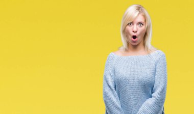 Korkuyor ve şok sürpriz ifade, korku ve heyecan yüz ile izole arka plan üzerinde kış kazak giyen genç güzel sarışın kadın.