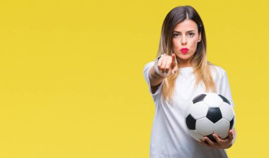 Futbol topu tutan genç güzel kadın kamera ve size parmak ile işaret arka plan izole, el işareti, pozitif ve kendinden emin bir jest ön