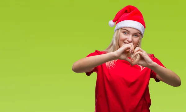 年轻的白种女人戴着圣诞帽子在孤独的背景微笑的爱显示心脏符号和形状与手 浪漫概念 — 图库照片