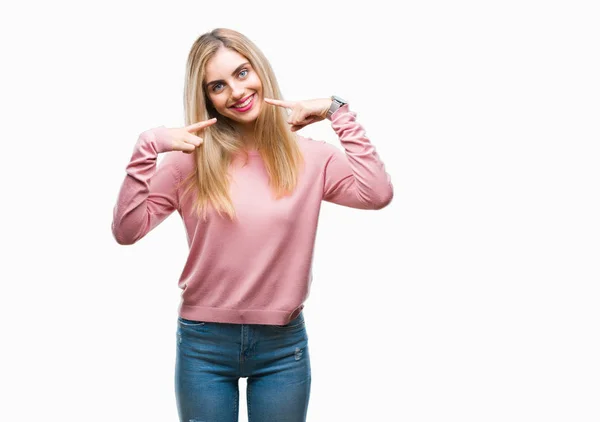 若い美しい金髪女性の自信を示すと指歯と口を指して笑って孤立の背景にピンク冬セーターを着ています 健康の概念 — ストック写真
