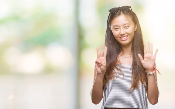 年轻的亚洲妇女戴着太阳镜在孤立的背景显示和指向手指八 而微笑着自信和快乐 — 图库照片