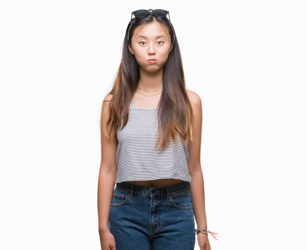 年轻的亚洲妇女戴着太阳镜在孤立的背景膨化脸颊与滑稽的脸 嘴被空气膨胀 疯狂的表情 — 图库照片