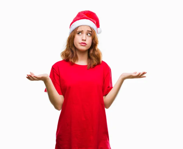 腕と手を上げてクリスマス帽子の無知と混乱して式を身に着けている孤立した背景に若くてきれいな女性 疑いのコンセプト — ストック写真