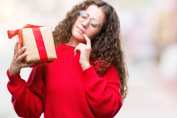 Young Brunette Girl Holding Gift Isolated Background Serious Face Thinking — Stock Photo, Image