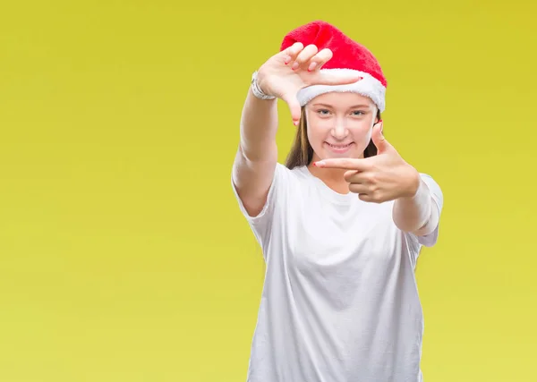 若い美しい白人女性の笑顔と幸せそうな顔で指手作りフレーム分離の背景にクリスマス帽子をかぶっています 創造性と写真のコンセプト — ストック写真