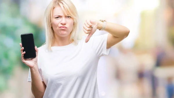 Young beautiful blonde woman showing screen of smartphone over isolated background with angry face, negative sign showing dislike with thumbs down, rejection concept