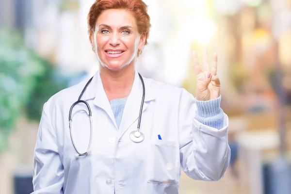 高级白种人医生妇女穿着医疗制服在孤立的背景显示和手指第三 同时微笑着自信和快乐 — 图库照片