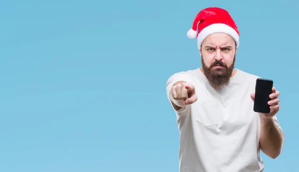 若い白人男着てクリスマス帽子表示スマート フォン画面カメラと指で指している孤立した背景に 手に署名 正面からポジティブで自信のジェスチャー — ストック写真