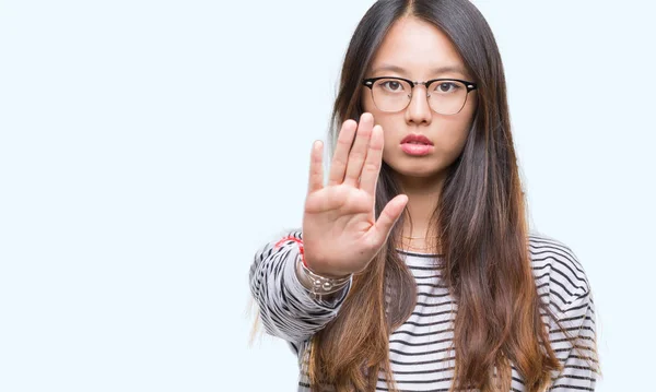 年轻的亚洲妇女戴着眼镜在孤立的背景下做停止唱歌与手掌的手 脸上带有否定和严肃手势的警告表达式 — 图库照片