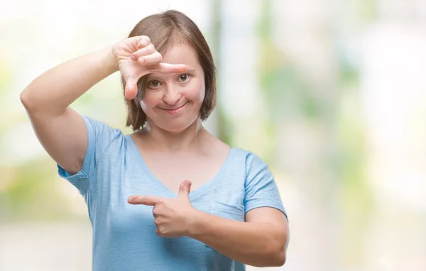 Young adult woman with down syndrome over isolated background smiling making frame with hands and fingers with happy face. Creativity and photography concept.