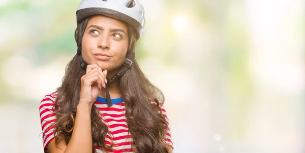 年轻的阿拉伯骑自行车妇女佩戴安全头盔在孤立的背景与手在下巴思考问题 沉思的表达 微笑着体贴的脸 怀疑概念 — 图库照片