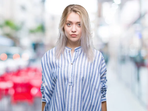 Young blonde woman over isolated background with serious expression on face. Simple and natural looking at the camera.