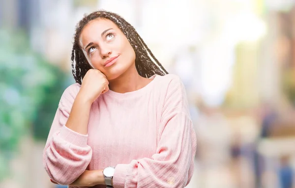 Young braided hair african american girl wearing sweater over isolated background with hand on chin thinking about question, pensive expression. Smiling with thoughtful face. Doubt concept.