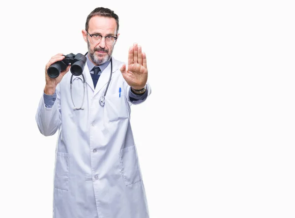 中年老年老板娘的医生通过双筒望远镜看孤立的背景与开放的手做停止标志与严肃和自信的表达 防御手势 — 图库照片