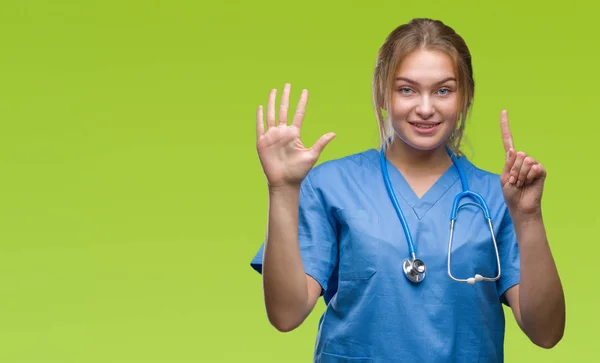 上外科医制服を着て若い白人医師女性分離を示す背景と自信を持って 幸せな笑みを浮かべて 指で上向きナンバーシックス — ストック写真