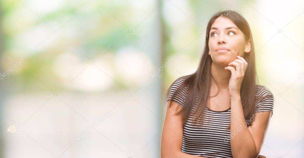 Young beautiful hispanic woman with hand on chin thinking about question, pensive expression. Smiling with thoughtful face. Doubt concept.