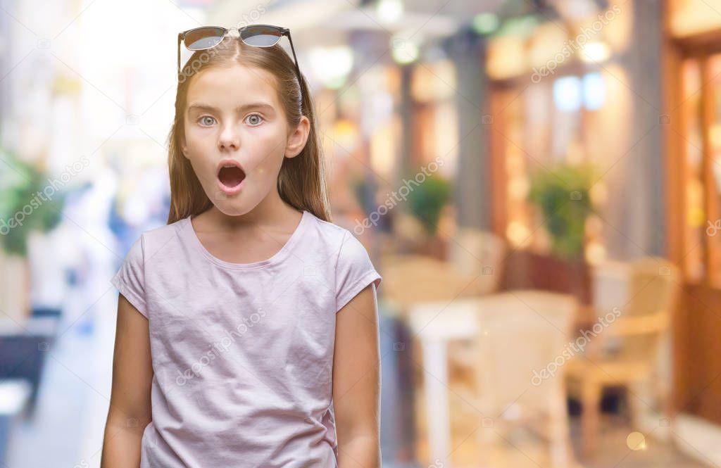 Young beautiful girl wearing sunglasses over isolated background afraid and shocked with surprise expression, fear and excited face.