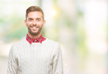 Yüzünde mutlu ve güzel bir gülümseme ile izole arka plan üzerinde kış kazak giyen genç yakışıklı adam. Şanslı kişi.