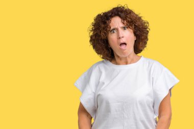 Beyaz giyen güzel orta ager üst düzey kadın şüpheci ve alaycı, t-shirt üzerine şok karşısında izole arka plan açık ağız ile şaşırttı.