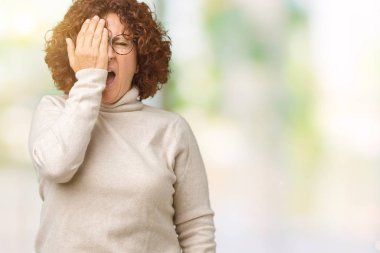 Boğazlı kazak ve gözlük yarım yüz, göz ve ağız el ile kapsayan Yawning yorgun izole arka plan üzerinde giyen güzel orta ager üst düzey kadın. Acı yüzü acıyor.