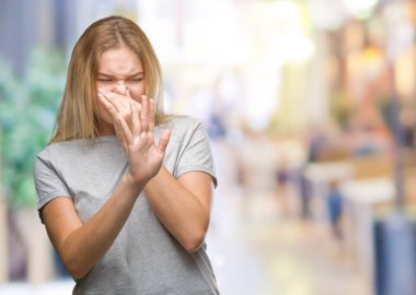 Bir şey pis ve iğrenç kokulu izole arka plan, dayanılmaz koku, holding nefes burun parmaklar ile genç beyaz kadın. Kötü kokuyor kavramı.