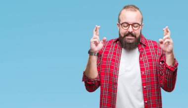 Umut ve gözleri kapalı geçiş parmaklarıyla gülümseyen izole arka plan üzerinde gözlük takan Genç beyaz hipster adam. Şans ve batıl kavramı.