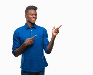 Gülümseyen ve iki elleri ve parmakları ile tarafına işaret kamera bakarak izole arka plan üzerinde genç Afro-Amerikan adam.